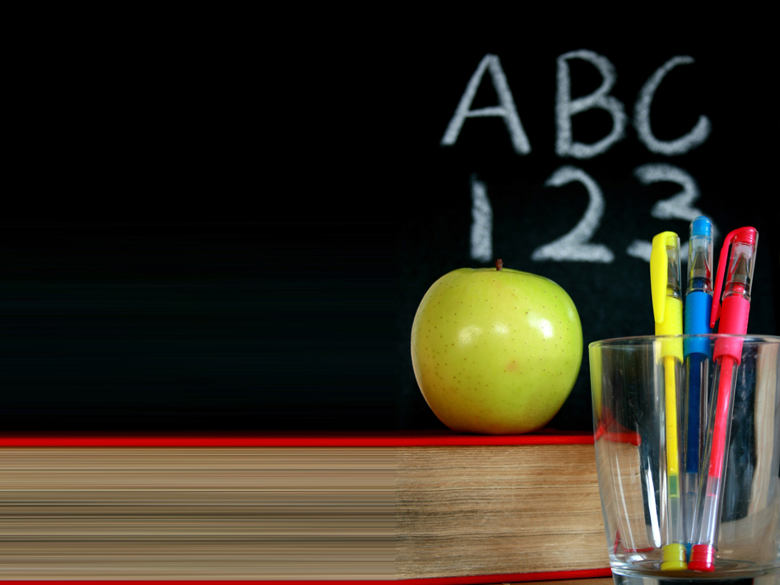 Chalkboard with a green apple and pens